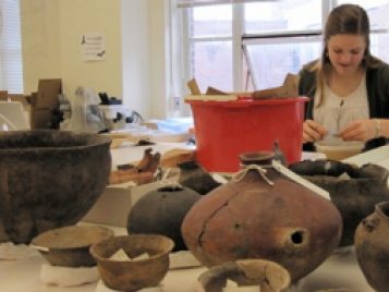 Graduate student working on a piece of pottery in an archaeological science lab.